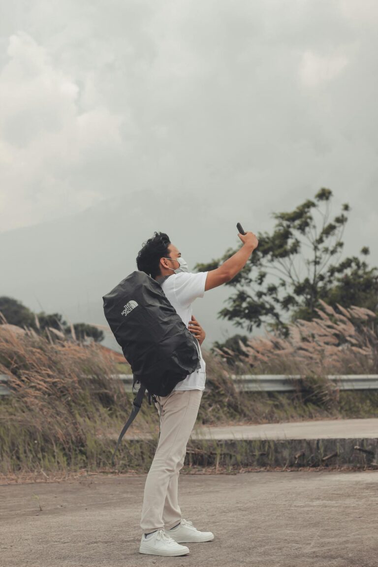 A man with a backpack takes a selfie in a scenic outdoor location. Ideal for travel and lifestyle themes.